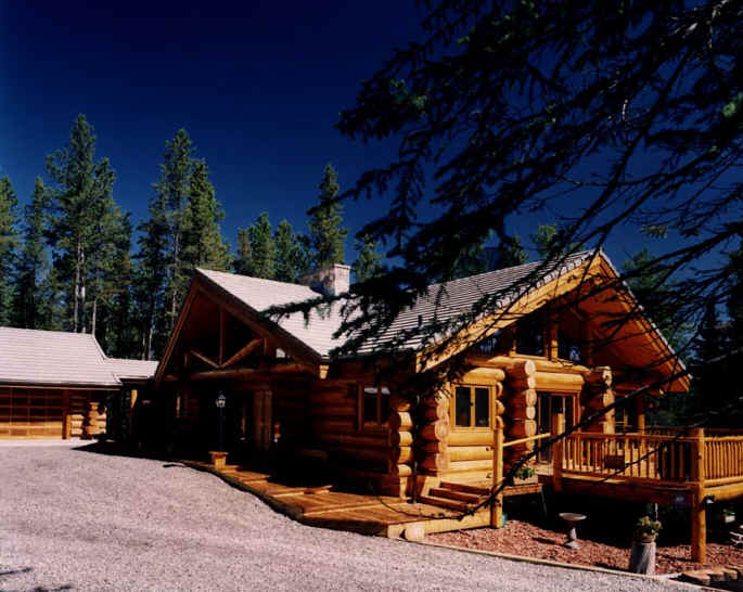 Gotowy dom z bali w Dobrzyniu nad Wisłą, z tarasem i przyległym garażem, otoczony drzewami iglastymi, widok z poziomu gruntu.